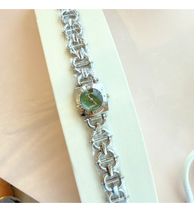 Relógio prateado com fundo verde